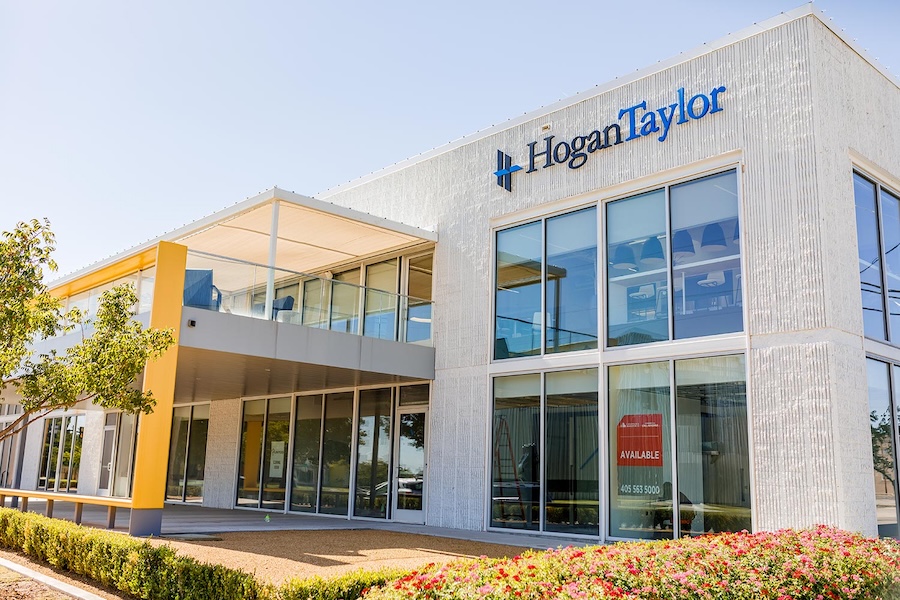 two-story commercial office building with glass storefront, HoganTaylor signage, and an available space sign