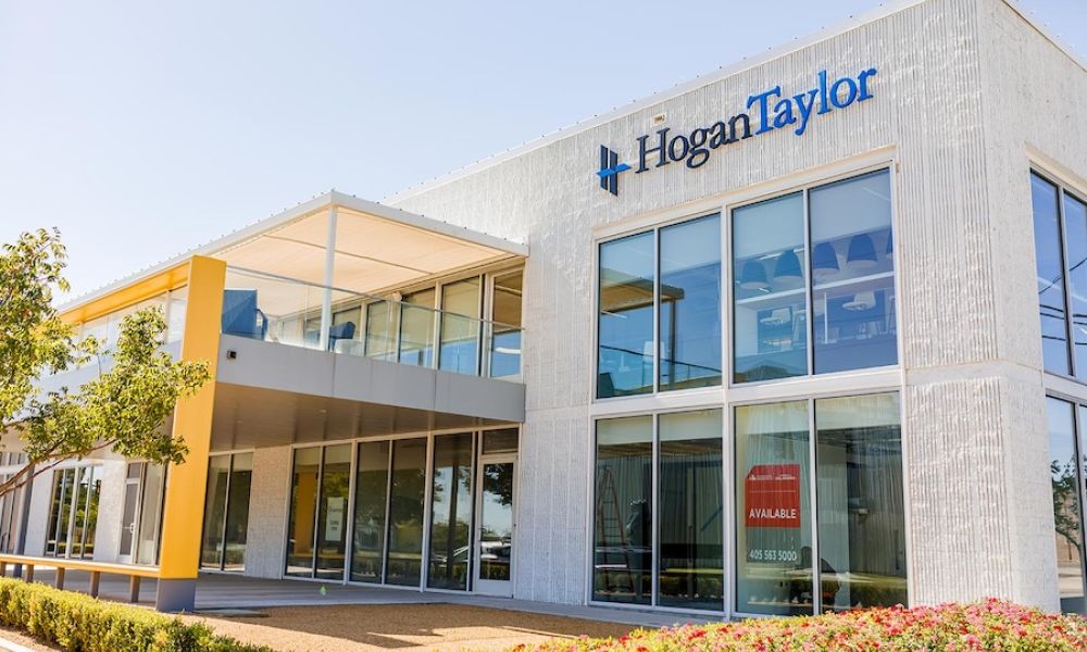 two-story commercial office building with glass storefront, HoganTaylor signage, and an available space sign